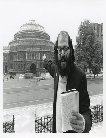 Item #41219 A b/w photograph by John &lsquo;Hoppy&rsquo; Hopkins of Allen Ginsberg, journal in hand, pointing towards the Royal Albert Hall from the other side of Kensington Gore in June 1965. POETS AT THE ALBERT MEMORIAL.