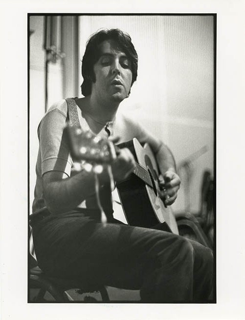 An original 10x8 b/w photograph by Linda McCartney of Paul McCartney playing acoustic guitar. Paul McCARTNEY.