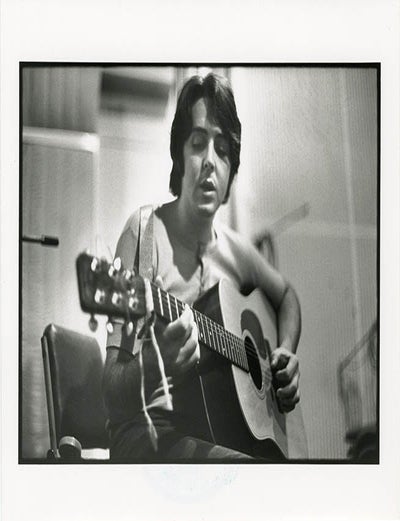 An original 8x10 b/w photograph by Linda McCartney of Paul McCartney playing acoustic guitar. Paul McCARTNEY.